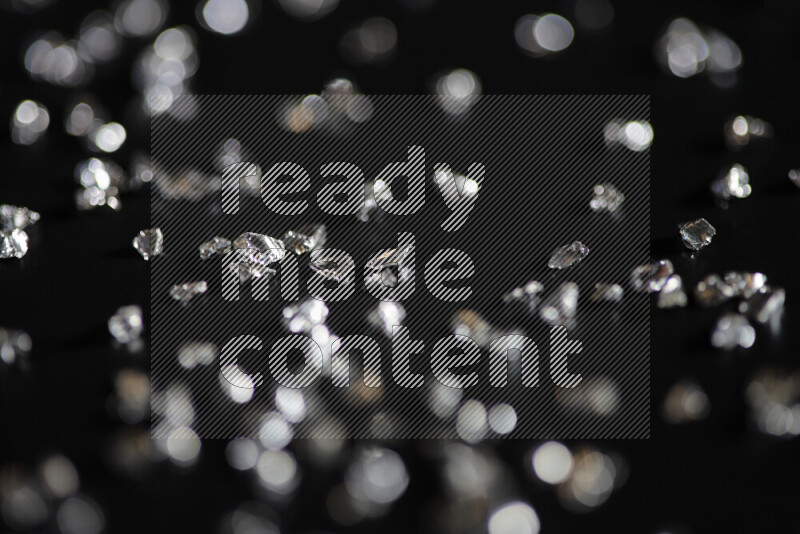 Silver shimmering fragments of glass scattered on a black background
