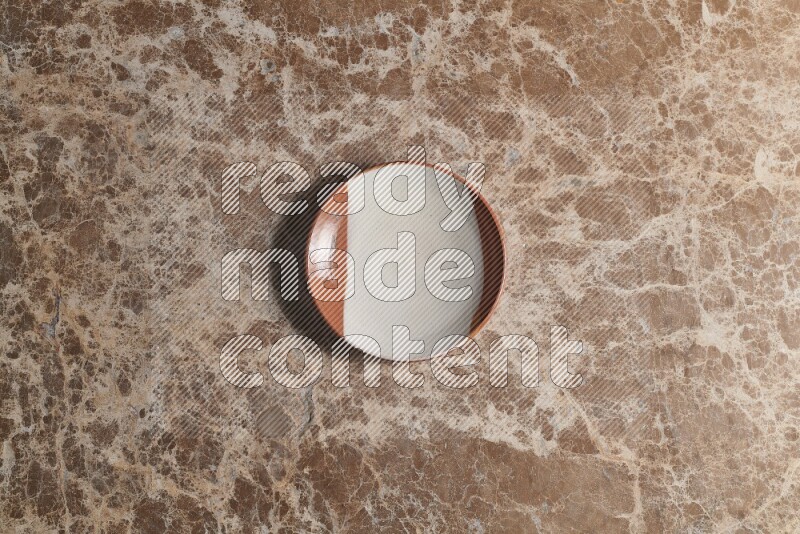 A decorative pottery plate on beige marble background
