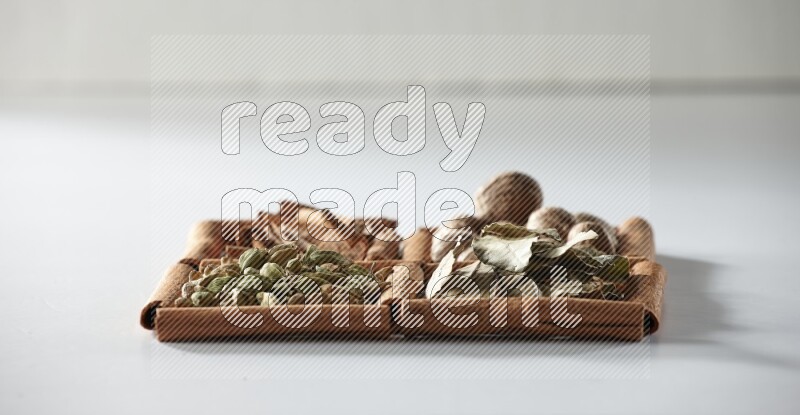 4 squares of cinnamon sticks full of nutmegs, bay laurel leaves, cardamom and cinnamon on white flooring