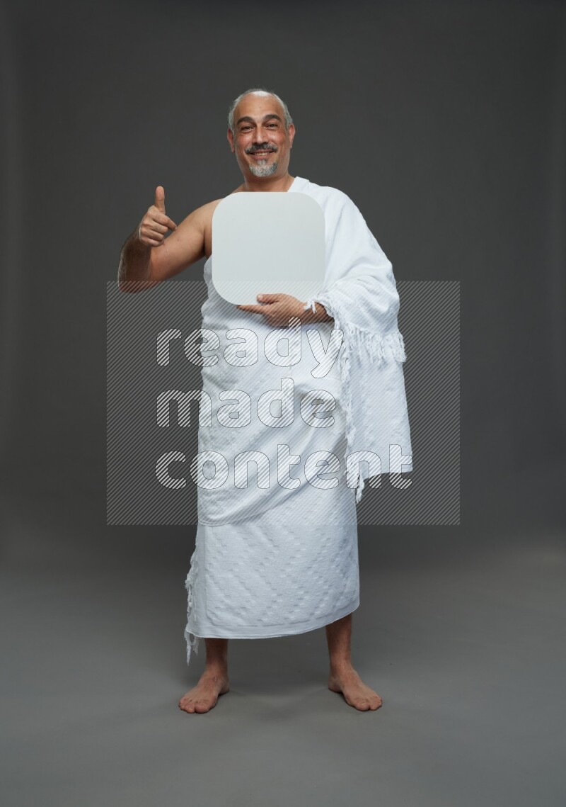 A man wearing Ehram Standing holding social media sign on gray background