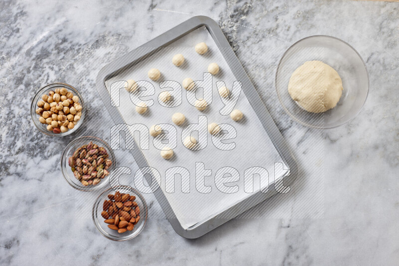 Ghoriba step by step with its ingredient, flour, powdered sugar, ghee and nuts on grey marble background