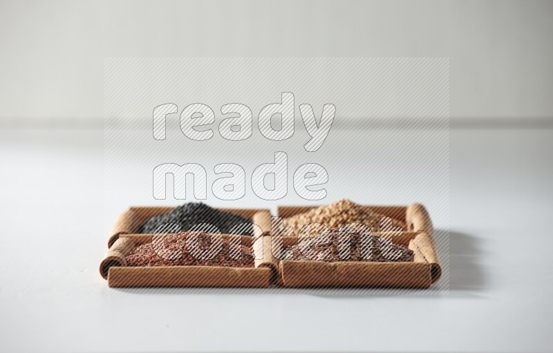 4 squares of cinnamon sticks full of black seeds, mustard seeds, flaxseeds and garden cress on white flooring