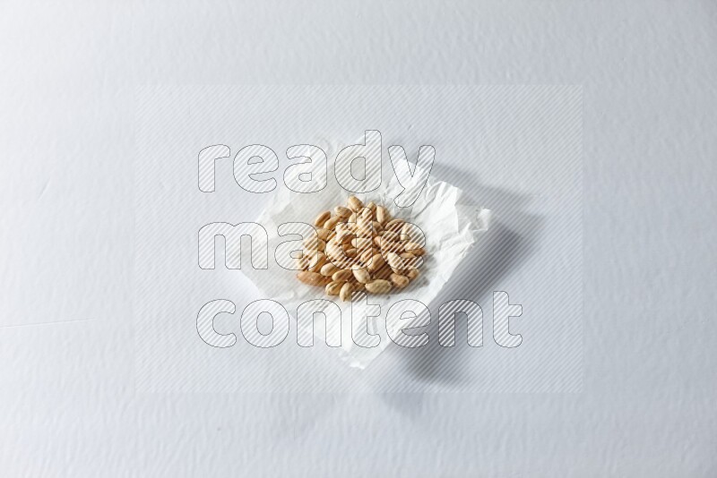 Peeled peanuts on a crumpled piece of paper on a white background in different angles
