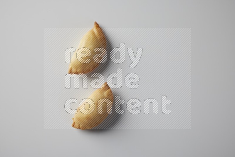 Two fried sambosa from a top angle on a white background