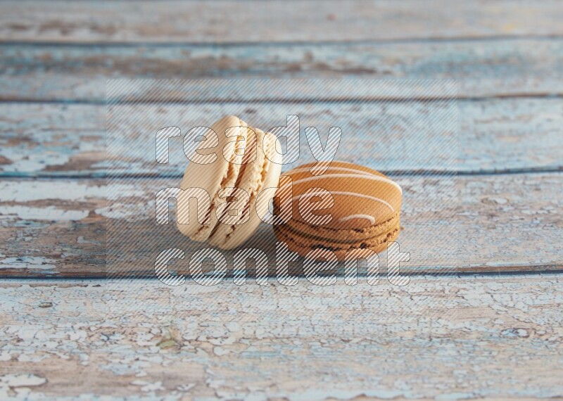 45º Shot of of two assorted Brown Irish Cream, and White Caramel fleur de sel macarons on light blue background