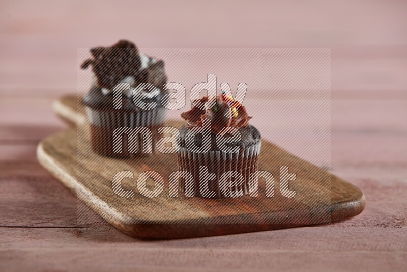 Chocolate mini cupcake topped with chocolate cream on a wooden board