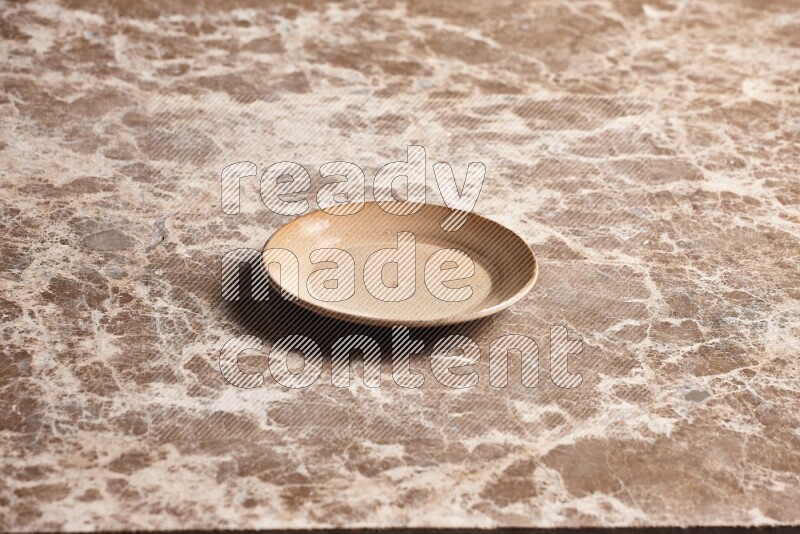 A beige pottery plate on beige marble background