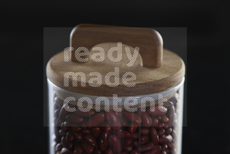 Red kidney beans in a glass jar on black background