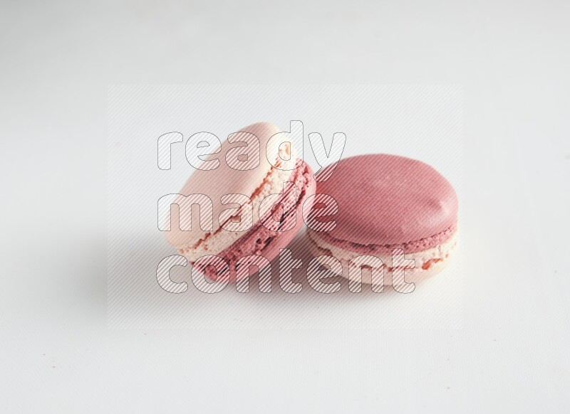 45º Shot of two Pink Litchi Raspberry macarons on white background