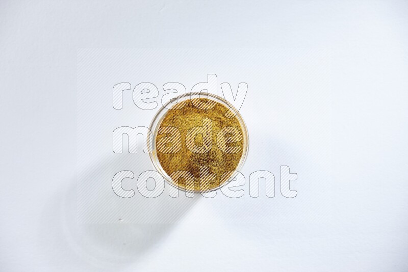 وعاء زجاجي ممتلئ ببودرة الكركم على خلفية بيضاء