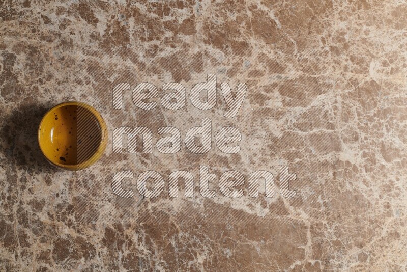 A multicolored pottery bowl on beige marble background