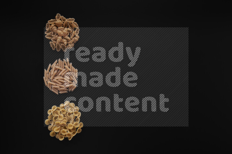 Different pasta types in 3 bunches on black background