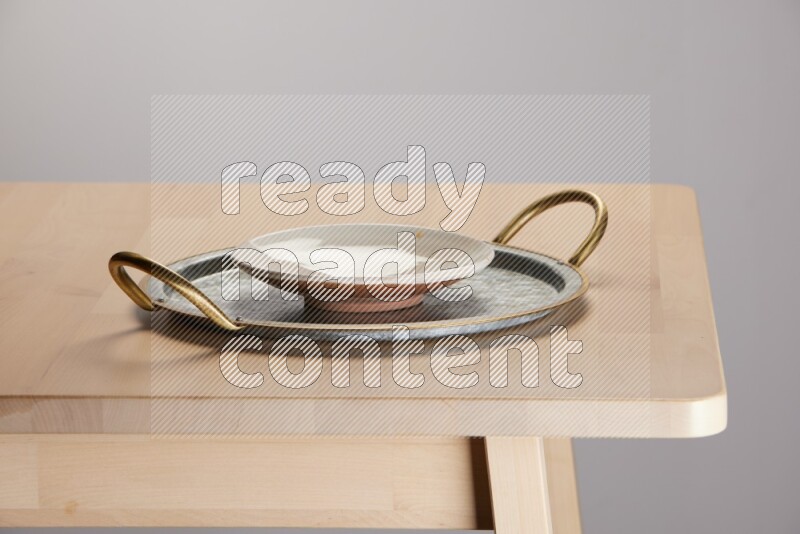 multicolored plate placed on a rounded stainless steel tray with golden handels on the edge of wooden table
