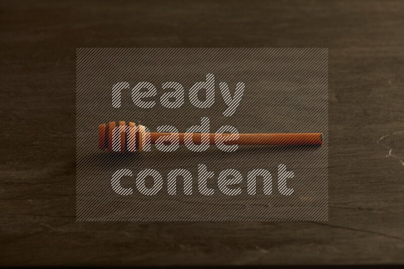 Wooden honey dipper on black slate background