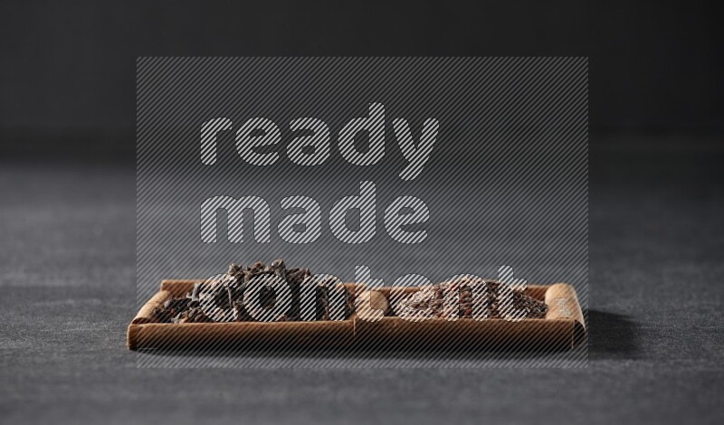 2 squares of cinnamon sticks full of flaxseeds and cloves on black flooring