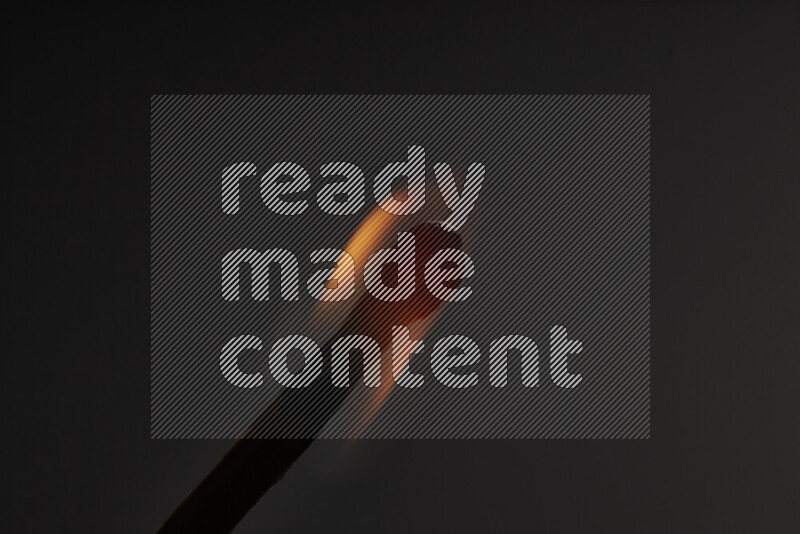 A burning matchstick isolated on dark backdrop