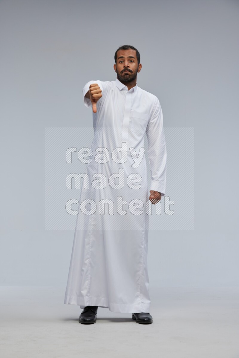 Saudi man Wearing Thob standing interacting with the camera on Gray background