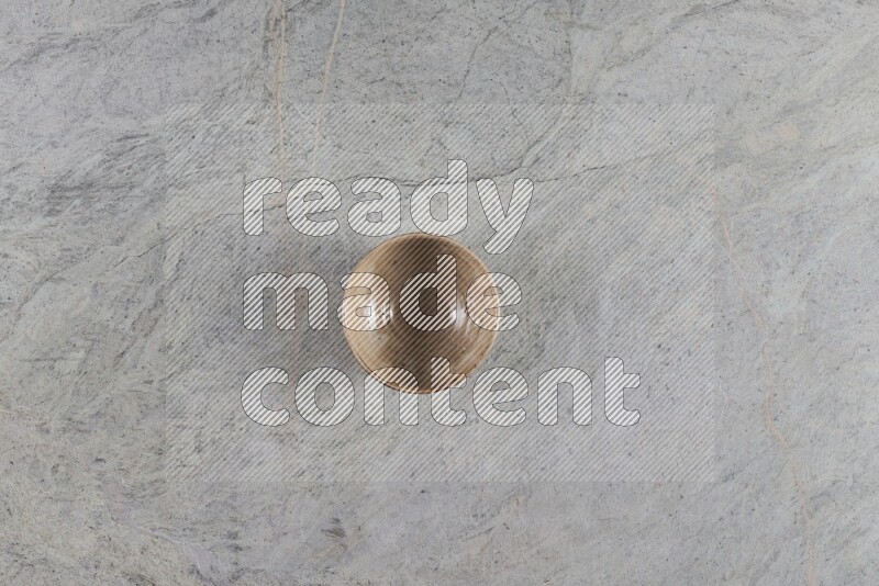 A small beige pottery bowl on grey marble background