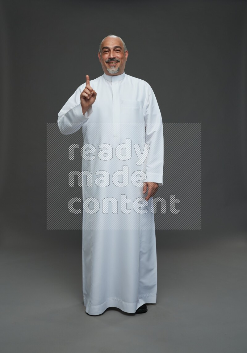 Saudi man without shomag Standing Interacting with the camera on gray background