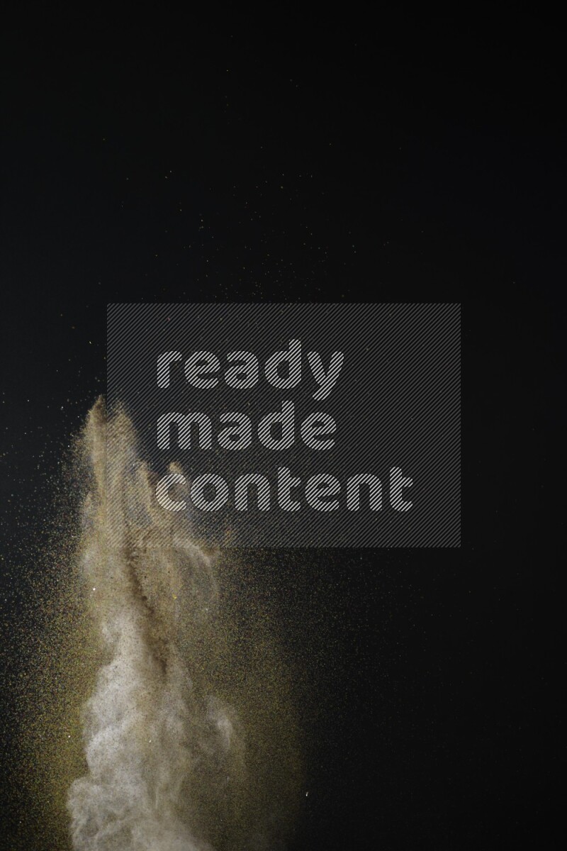 A side view of brown powder explosion on black background