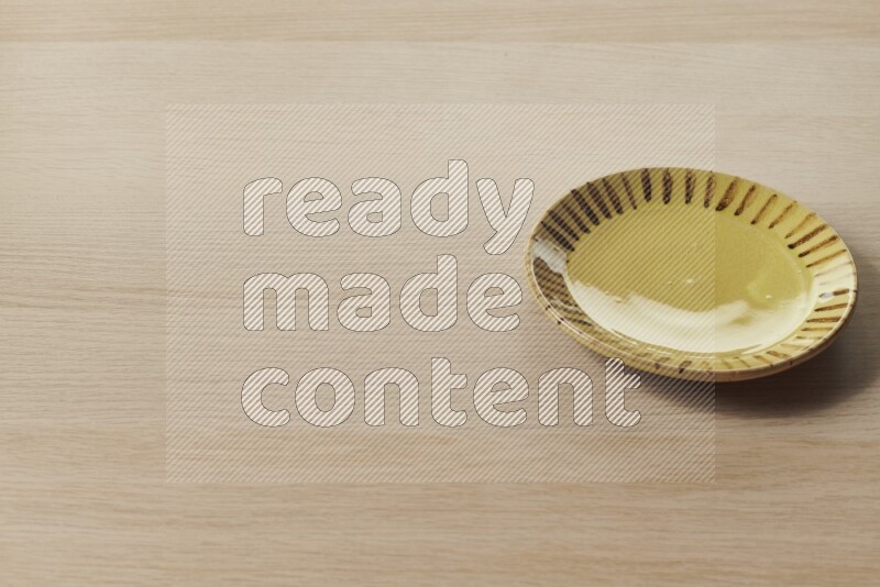 A multicolored pottery plate on light wooden background