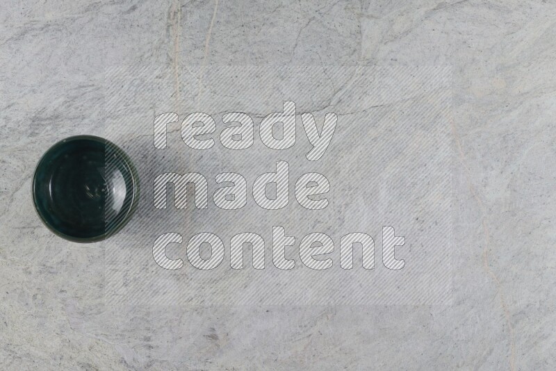 A dark green pottery bowl on grey marble background