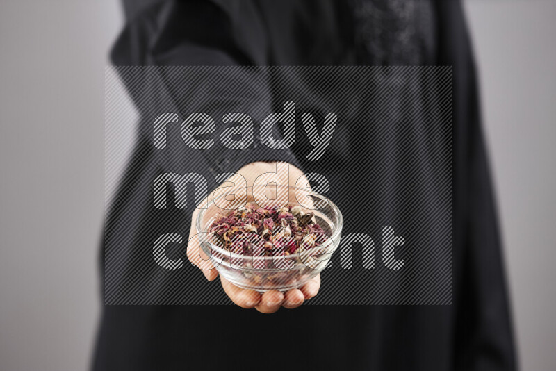 Woman in abaya holding different kinds of spices in different positions