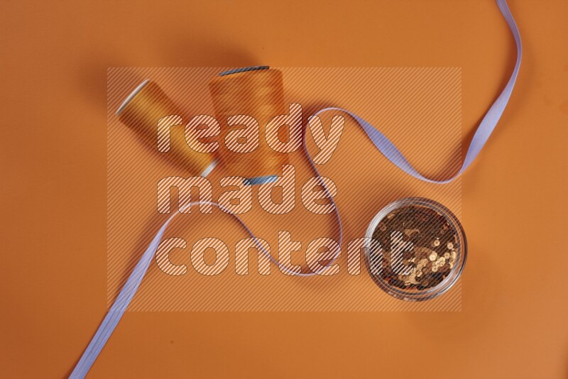 مجموعة من أدوات الخياطة والتفصيل أرجوانية اللون على خلفية برتقالية