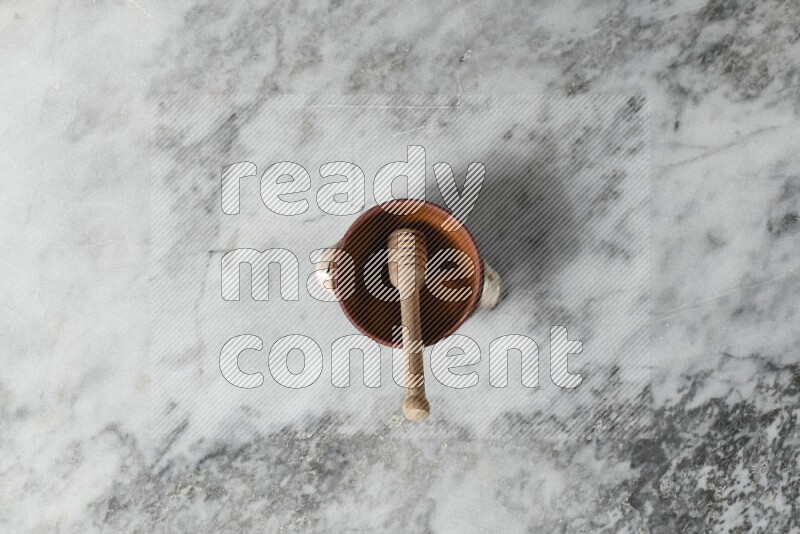 Decorative Pottery Pot with wooden honey handle in it, on grey marble flooring, Top View