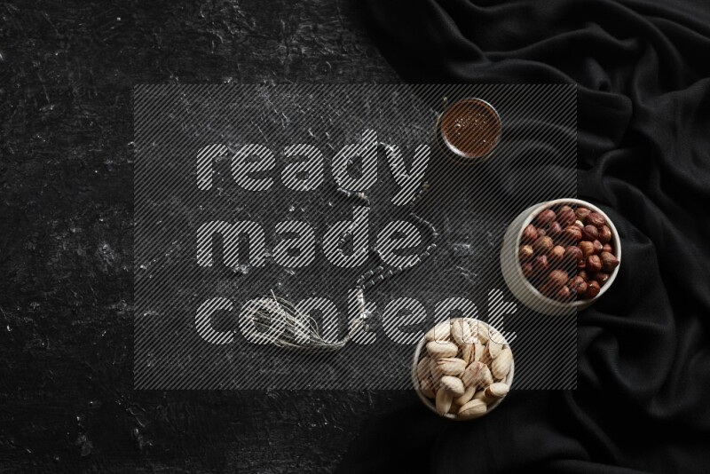 Nuts in pottery bowls with coffee in a dark setup