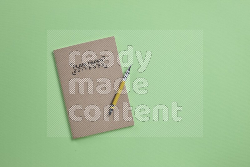 A notebook with different school supplies on green background