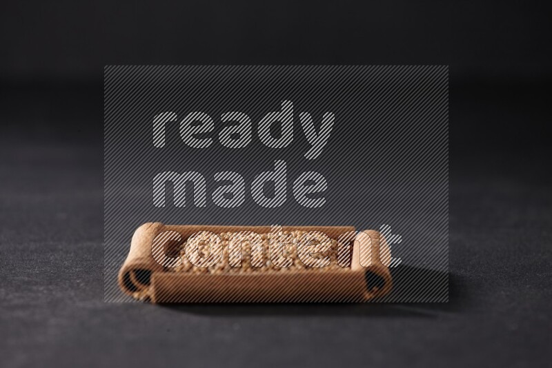 أربعة من أعواد القرفة مكونة شكل مربع بداخلها حبوب الخردل علي خلفية سوداء