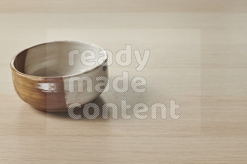 A multicolored pottery bowl on light wooden background