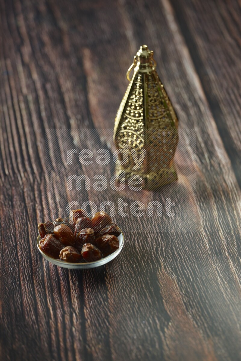 A golden lantern with different drinks, dates, nuts, prayer beads and quran on brown wooden background