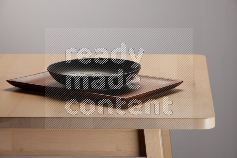 black plate on a rectangular wooden tray on the edge of wooden table