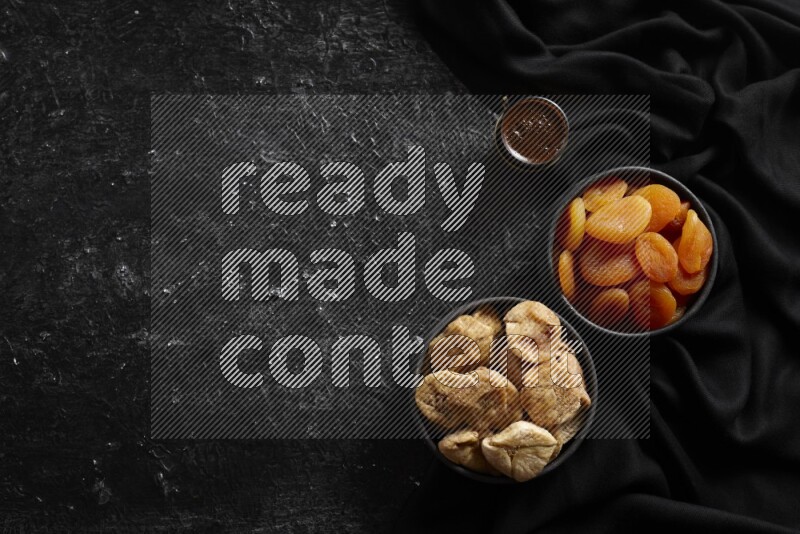 Dried fruits in pottery bowls with coffee in a dark setup
