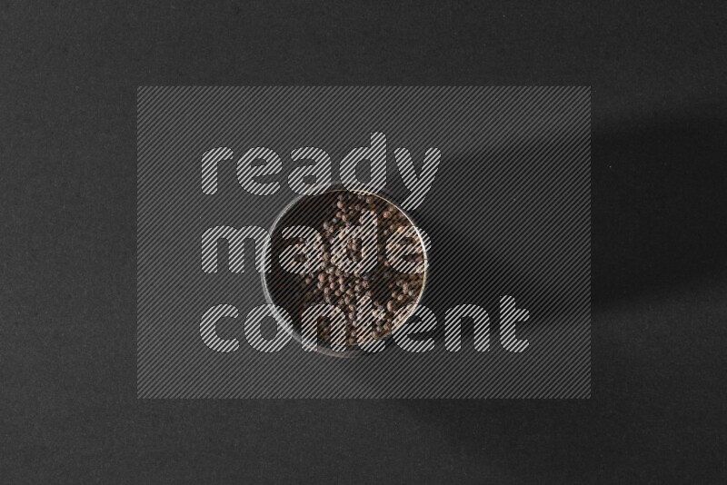 حبوب الفلفل الأسود في وعاء فخاري أسود علي خلفية سوداء