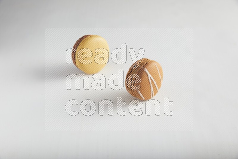 45º Shot of of two assorted Brown Irish Cream, and Yellow, and Brown Chai Latte macarons on white background