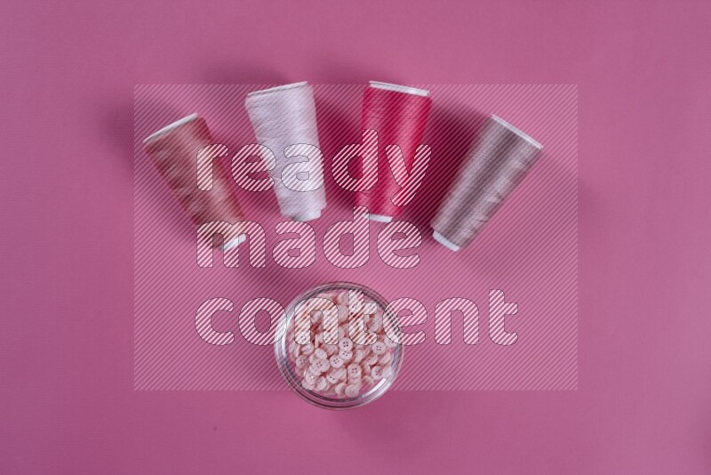 A pink collection of sewing and tailoring tools arranged on a pink background