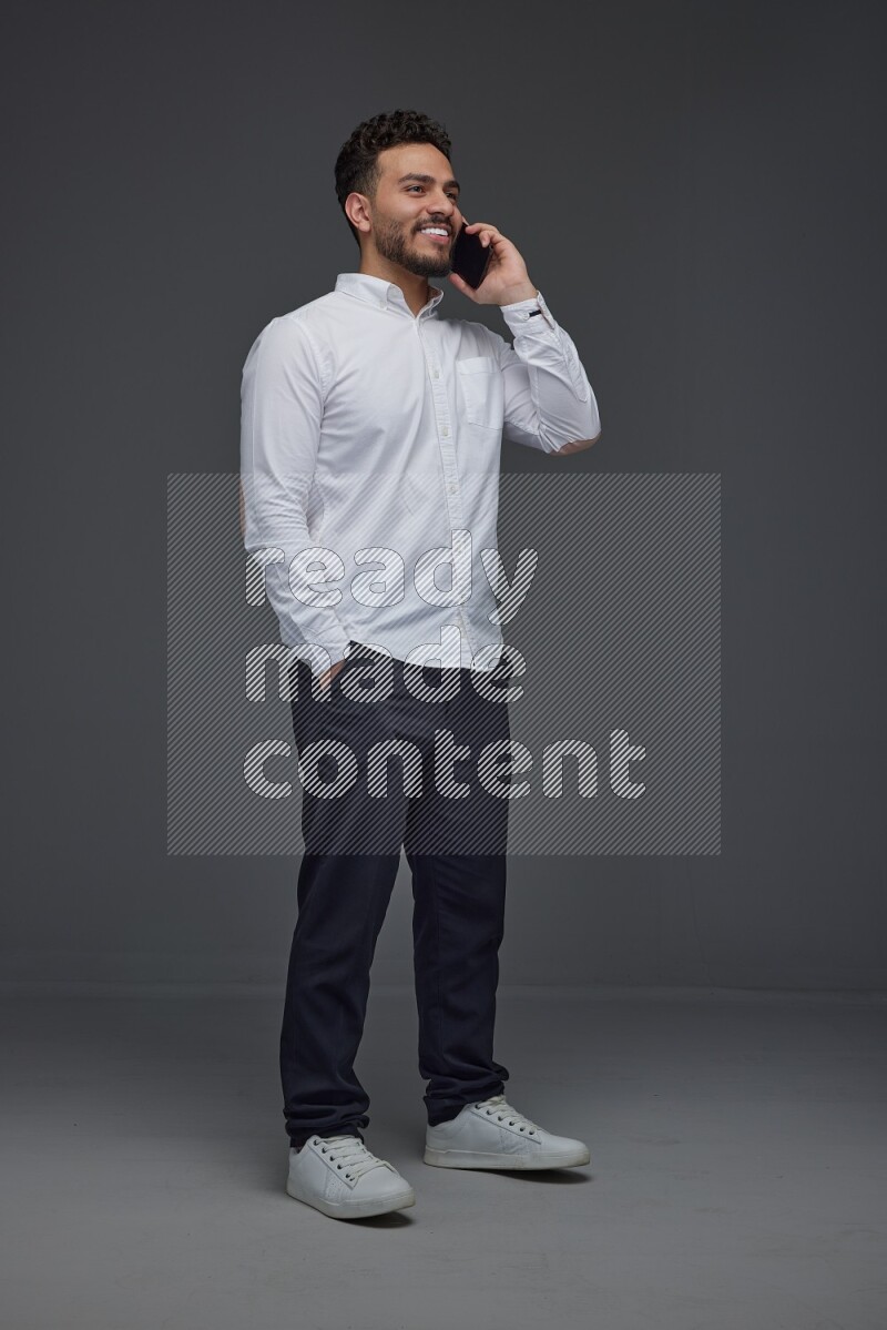 A man wearing smart casual talking in the phone eye level on a gray background