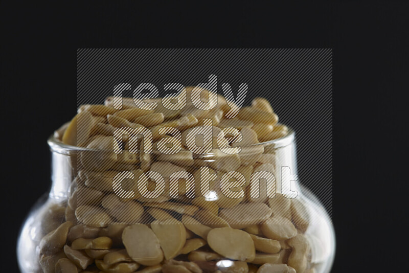 Crushed beans in a glass jar on black background