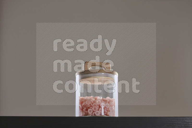 أزرار متنوعة في وعاء زجاجي علي خلفية سوداء