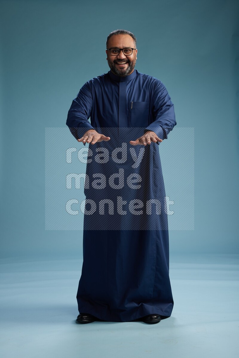 Saudi Man without shimag Standing Interacting with the camera on blue background