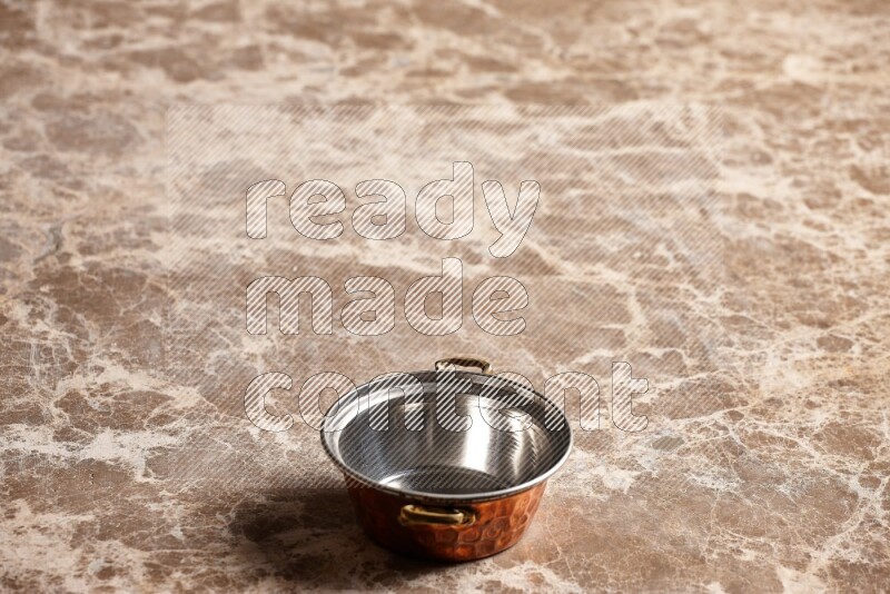 A small copper pot on beige marble background