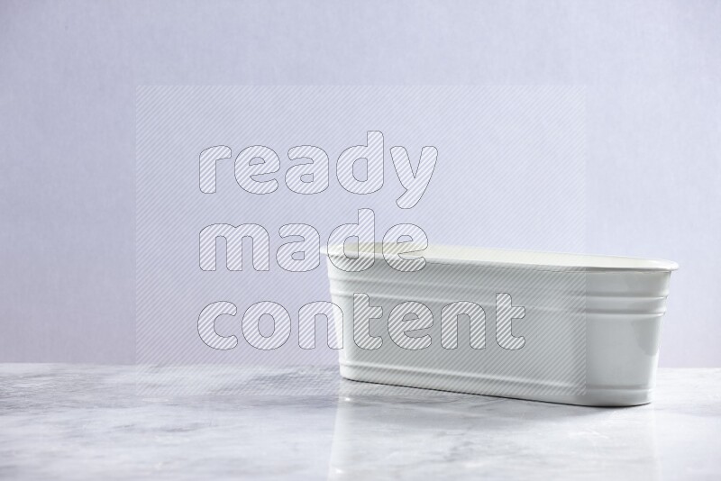 An empty white plant pot on grey marble background