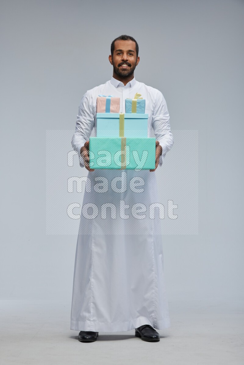 Saudi man Wearing thob standing holding gift box on Gray background
