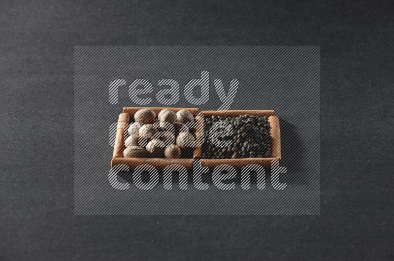 2 squares of cinnamon sticks full of nutmegs and black peppers on black flooring