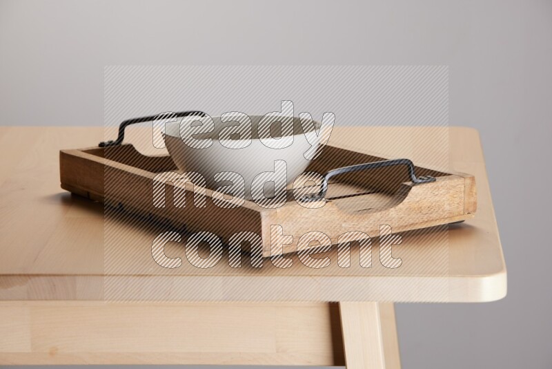 off white bowl on a light colored rectangular wooden tray with handles