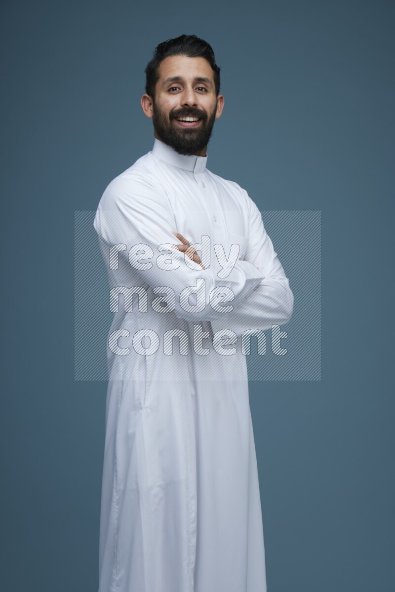 A man posing in a blue background wearing Saudi Thob