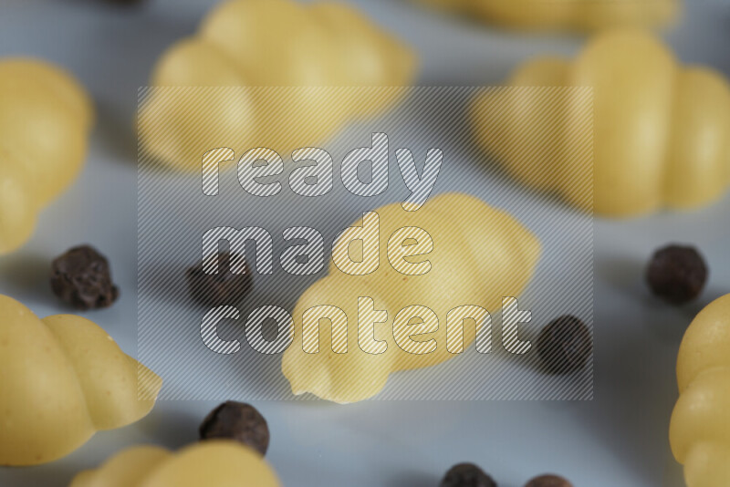Raw pasta with different ingredients such as cherry tomatoes, garlic, onions, red chilis, black pepper, white pepper, bay laurel leaves, rosemary, cardamom and mushrooms on light blue background